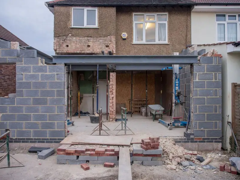 Bricklayer laying a course of bricks on a house extension wall