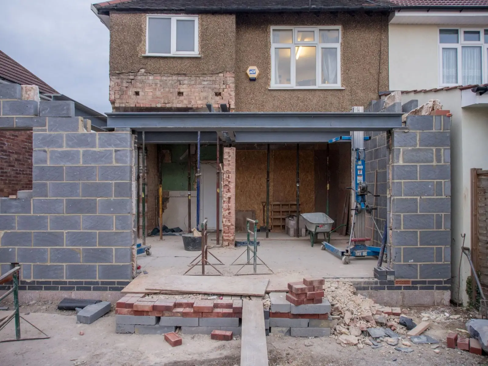 Bricklayer laying a course of bricks on a house extension wall