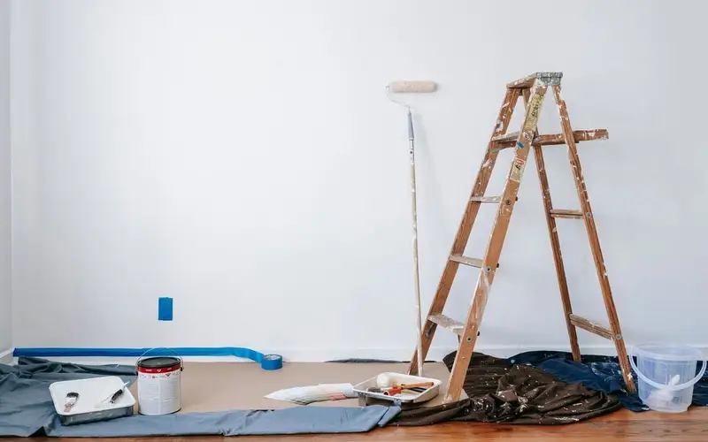 Decorator on a ladder painting an interior wall with a roller
