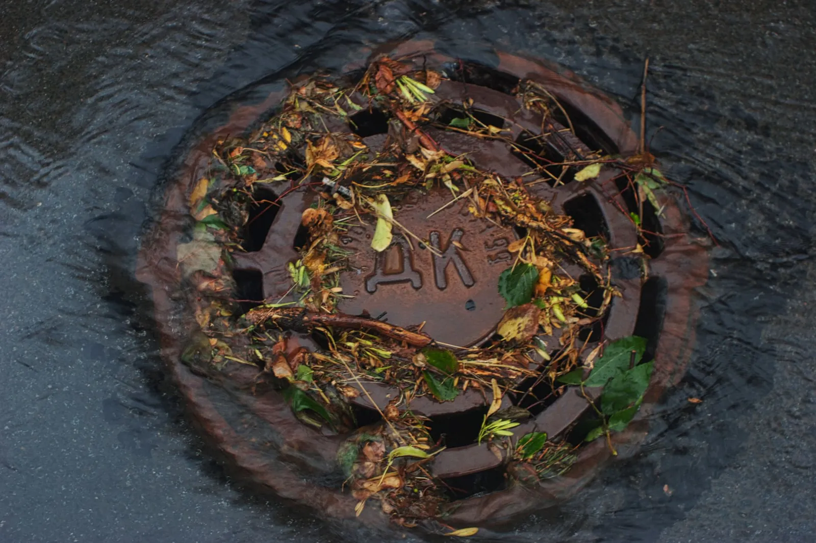 Worker in hi-vis lifting a drain cover on a residential street