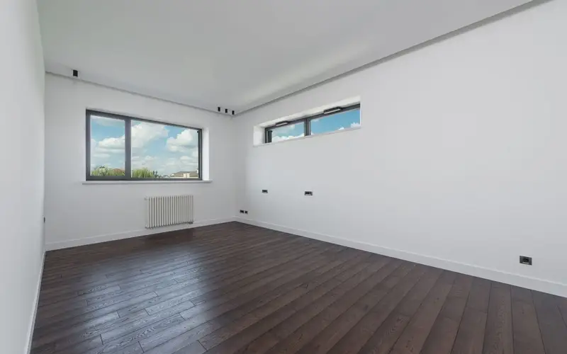 Worker fitting oak-effect laminate flooring in a bright room
