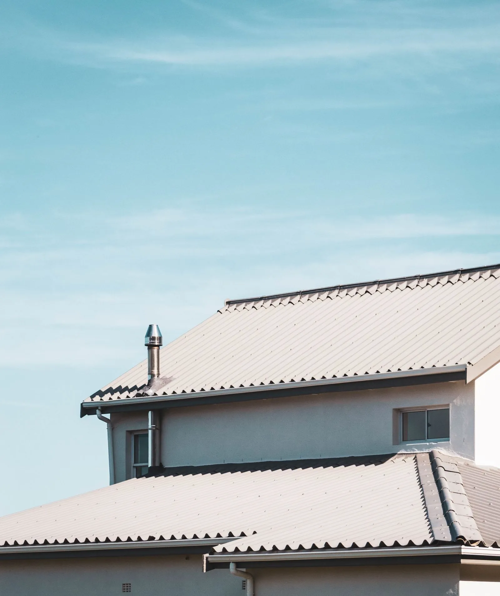 Roofline and gutters on a house against a bright sky