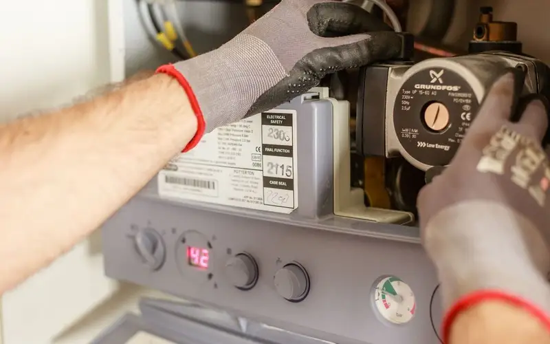 Plumber tightening pipework under a kitchen sink with a wrench