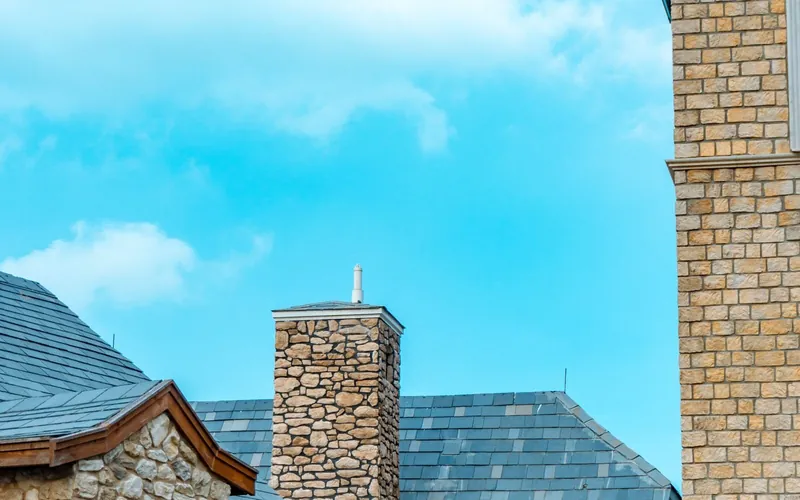 Slate roofs and stone chimney stacks against a blue sky