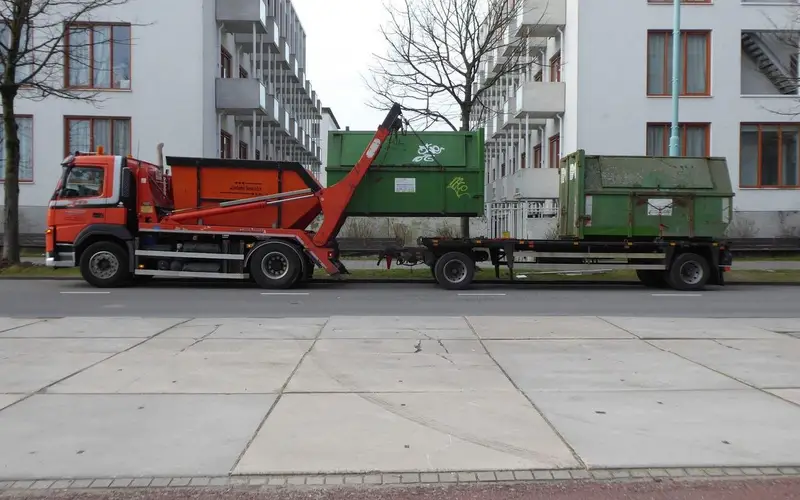 Worker loading household waste into a caged tipper van